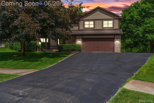 2206 Estates Dr, Highland, MI 48357 - view of front facade with brick siding, asphalt driveway, an attached garage, and a lawn