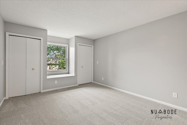 1427 Atlantic St NW, Grand Rapids, MI 49504 - unfurnished bedroom with multiple closets, carpet floors, and a textured ceiling