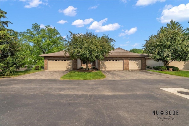 1427 Atlantic St NW, Grand Rapids, MI 49504 - view of property hidden behind natural elements with a garage, asphalt driveway, and brick siding