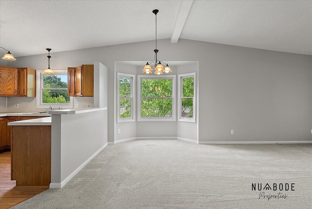 1427 Atlantic St NW, Grand Rapids, MI 49504 - kitchen with brown cabinets, light carpet, a chandelier, light countertops, and decorative light fixtures