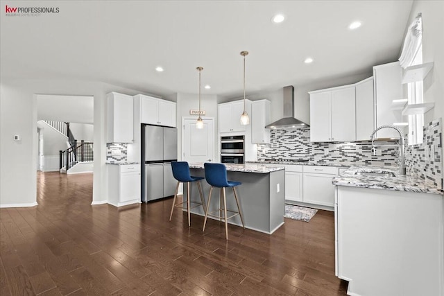 945 Reef Dr, Canton, MI 48187 - kitchen featuring wall chimney range hood, stainless steel appliances, a kitchen island, decorative backsplash, and white cabinetry