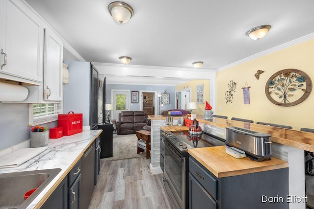 204 Maple St, Durand, MI 48429 - kitchen with electric stove, butcher block countertops, open floor plan, light wood-style floors, and white cabinets