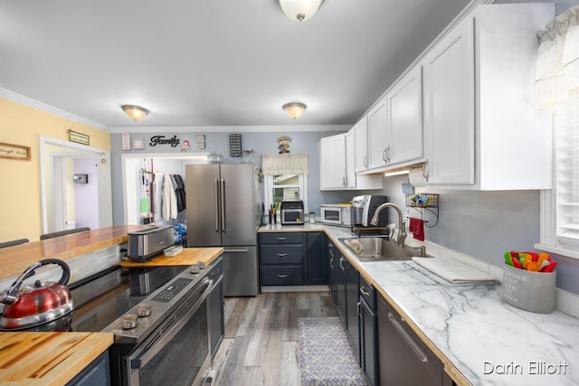 204 Maple St, Durand, MI 48429 - kitchen featuring stainless steel appliances, white cabinetry, light wood finished floors, crown molding, and wood counters