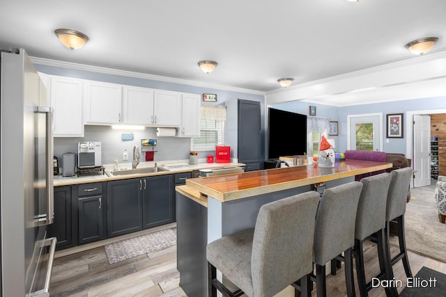 204 Maple St, Durand, MI 48429 - kitchen with stainless steel refrigerator, a kitchen bar, plenty of natural light, ornamental molding, and open floor plan
