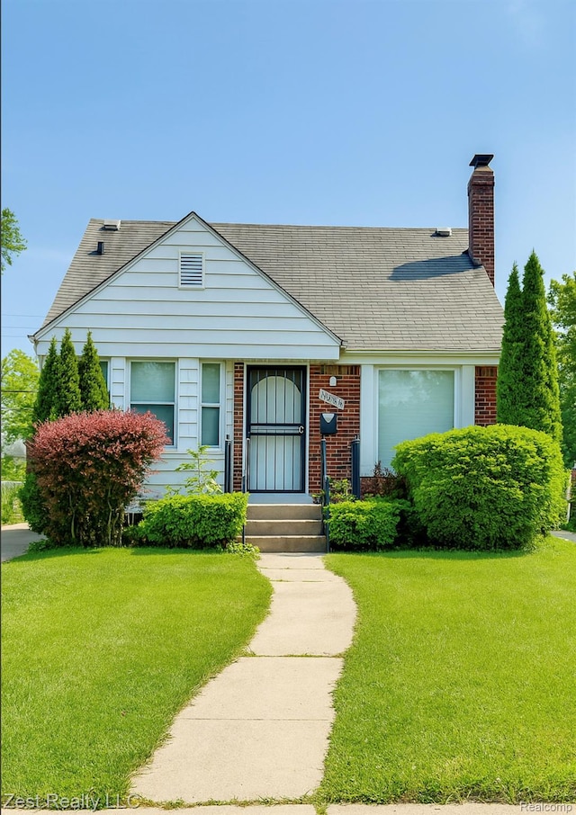 15684 Manning St, Detroit, MI 48205 - view of front of house featuring a front lawn, a chimney, brick siding, and roof with shingles