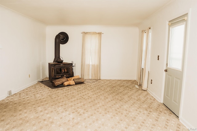 8667 Thompson Hwy, Blissfield, MI 49228 - unfurnished living room featuring a wood stove and carpet floors