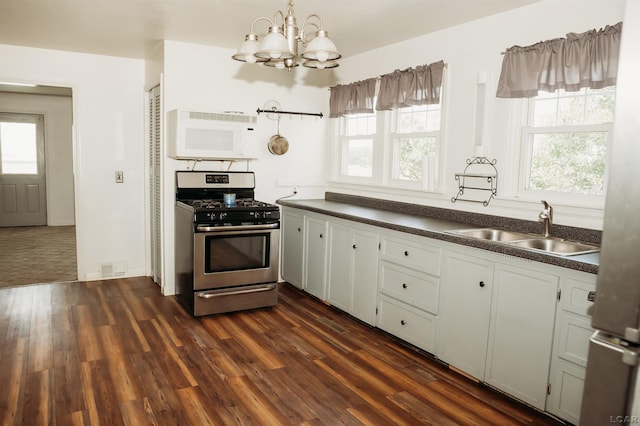 8667 Thompson Hwy, Blissfield, MI 49228 - kitchen with stainless steel gas range, white microwave, dark countertops, a chandelier, and healthy amount of natural light
