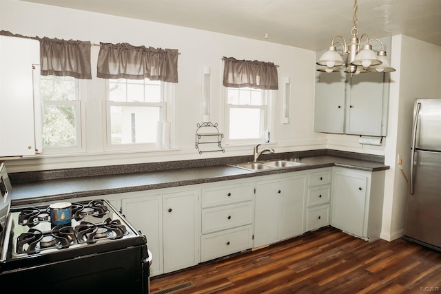 8667 Thompson Hwy, Blissfield, MI 49228 - kitchen with gas range, freestanding refrigerator, a chandelier, dark countertops, and white cabinets