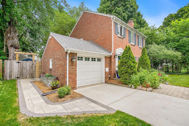 1515 E Stadium Blvd, Ann Arbor, MI 48104 - view of home's exterior with brick siding, an attached garage, concrete driveway, a chimney, and roof with shingles