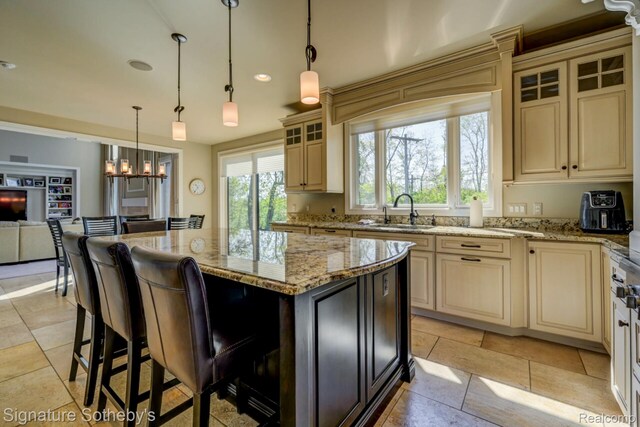 3225 Legacy Ct, West Bloomfield, MI 48323 - kitchen featuring cream cabinets, glass insert cabinets, light stone countertops, a kitchen island, and a breakfast bar