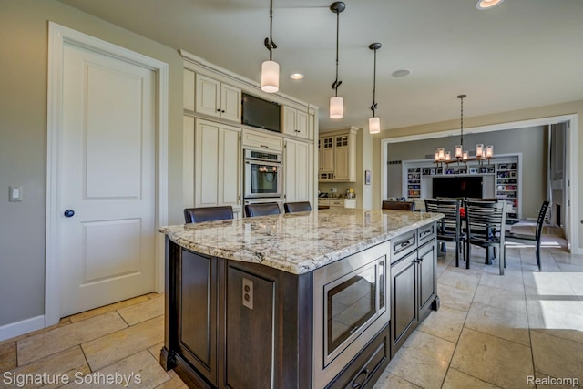 3225 Legacy Ct, West Bloomfield, MI 48323 - kitchen with stainless steel appliances, cream cabinetry, light stone countertops, a chandelier, and hanging light fixtures