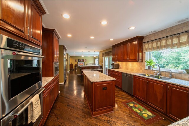 4683 Maura Ln, West Bloomfield, MI 48323 - kitchen with stainless steel appliances, a kitchen island, light stone counters, dark wood-style floors, and tasteful backsplash