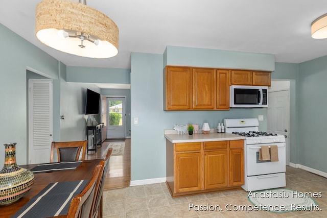 4516 Burgis Ave SE, Grand Rapids, MI 49508 - kitchen with stainless steel microwave, white range with gas stovetop, light countertops, and brown cabinets