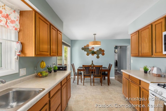 4516 Burgis Ave SE, Grand Rapids, MI 49508 - kitchen with brown cabinets, light countertops, decorative light fixtures, and white range with gas cooktop
