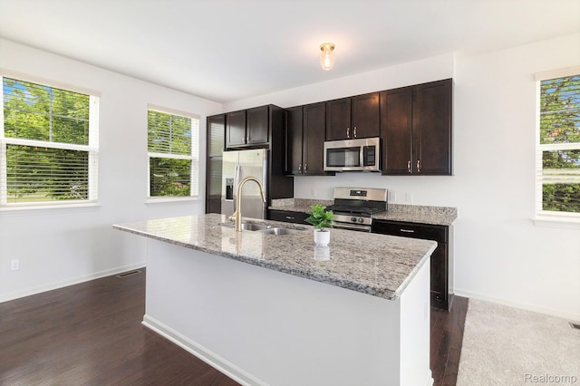 478 N Wixom Rd, Wixom, MI 48393 - kitchen with appliances with stainless steel finishes, dark wood-style flooring, a kitchen island with sink, dark brown cabinetry, and light stone countertops