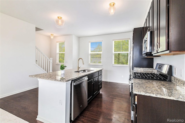 478 N Wixom Rd, Wixom, MI 48393 - kitchen featuring appliances with stainless steel finishes, dark wood-style floors, a center island with sink, and light stone countertops