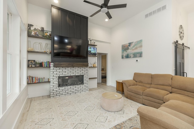 21536 Fieldview Dr, Edwardsburg, MI 49112 - living room featuring light wood-style flooring, a barn door, a ceiling fan, a fireplace, and recessed lighting