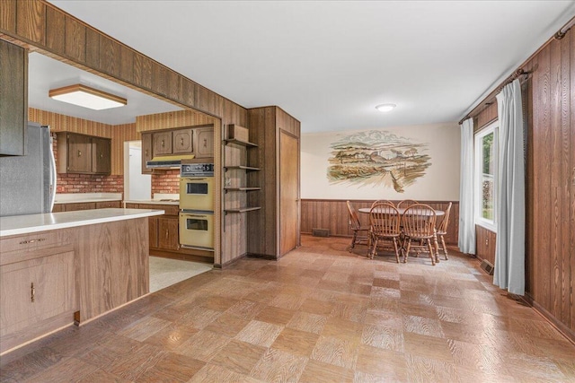360 Wood Creek Dr, Howell, MI 48843 - kitchen featuring multiple ovens, light countertops, open shelves, wooden walls, and wainscoting