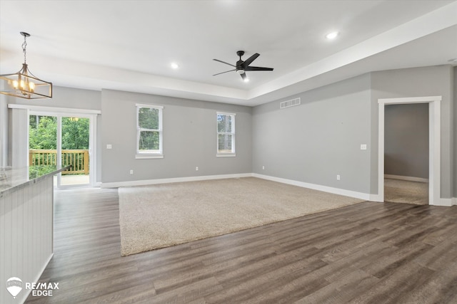 3113 Harbor Pointe Cir, Fenton, MI 48430 - unfurnished living room featuring wood finished floors, ceiling fan, a tray ceiling, recessed lighting, and a chandelier