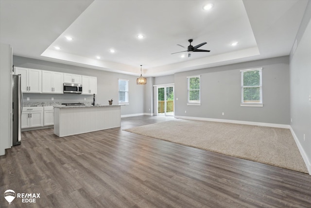 3113 Harbor Pointe Cir, Fenton, MI 48430 - unfurnished living room featuring a raised ceiling, ceiling fan, recessed lighting, and dark wood-type flooring