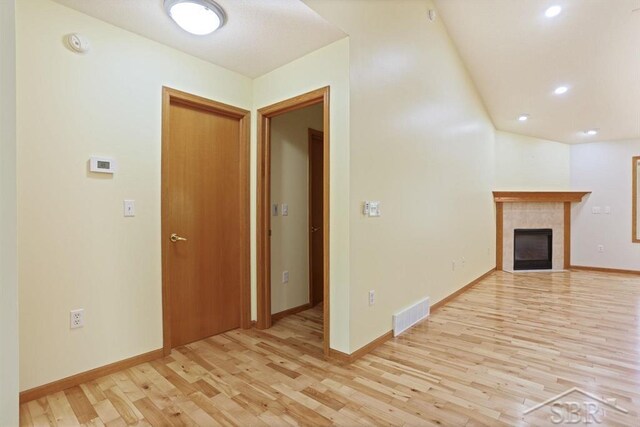 878 S Crooked Tree Ln, Midland, MI 48640 - unfurnished living room featuring light wood finished floors, a tiled fireplace, and recessed lighting