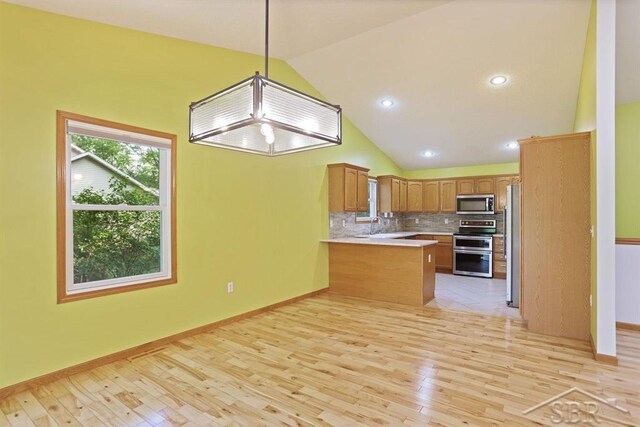 878 S Crooked Tree Ln, Midland, MI 48640 - kitchen featuring stainless steel appliances, a peninsula, light wood-style floors, lofted ceiling, and light countertops