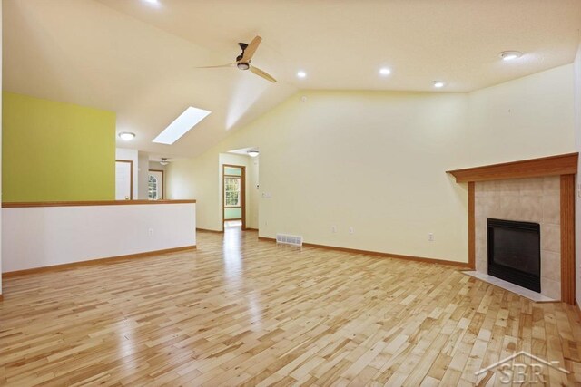 878 S Crooked Tree Ln, Midland, MI 48640 - unfurnished living room featuring ceiling fan, light wood-style flooring, a tile fireplace, recessed lighting, and a skylight