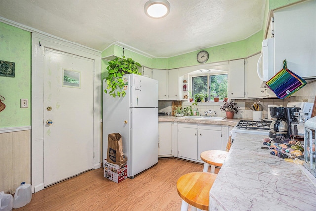 316 Reed Ave, Kalamazoo, MI 49001 - kitchen with white appliances, light wood-style floors, light countertops, white cabinets, and tasteful backsplash