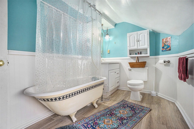 316 Reed Ave, Kalamazoo, MI 49001 - bathroom with wood finished floors, a freestanding bath, lofted ceiling, a wainscoted wall, and curtained shower