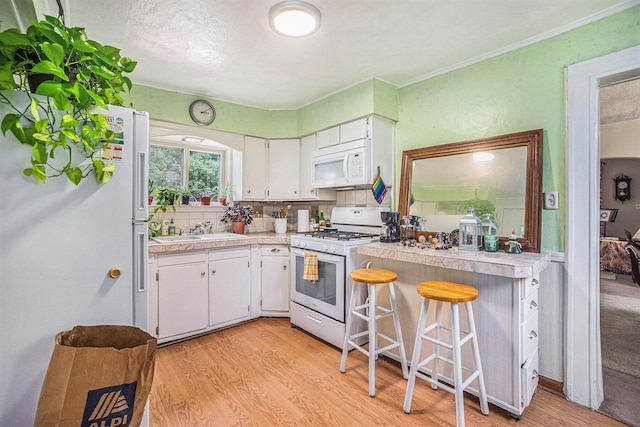 316 Reed Ave, Kalamazoo, MI 49001 - kitchen featuring white appliances, light wood-type flooring, white cabinets, light countertops, and ornamental molding