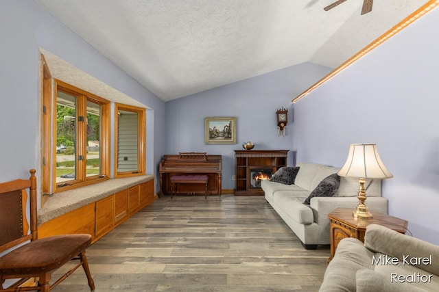 2742 Woodridge Dr, Jenison, MI 49428 - living room with vaulted ceiling, light wood-type flooring, a warm lit fireplace, ceiling fan, and a textured ceiling