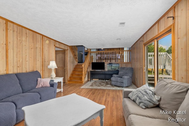 2742 Woodridge Dr, Jenison, MI 49428 - living room with wooden walls, stairway, wood finished floors, and a textured ceiling