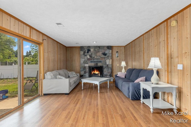 2742 Woodridge Dr, Jenison, MI 49428 - living room with wood walls, a fireplace, light wood-style flooring, a textured ceiling, and crown molding