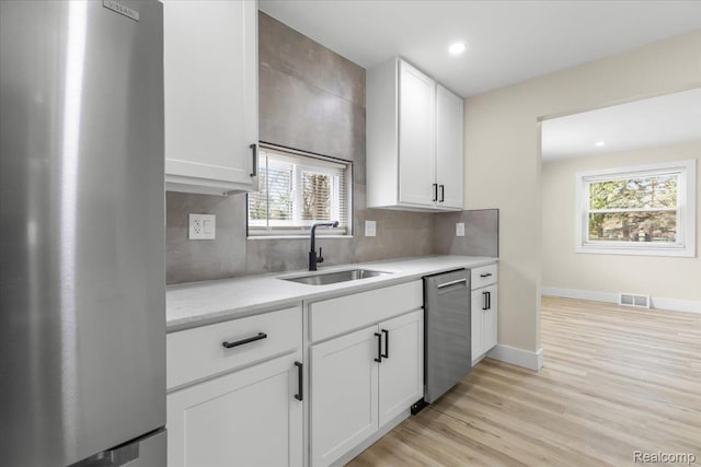 24270 Columbus Ave, Warren, MI 48089 - kitchen featuring stainless steel appliances, white cabinetry, decorative backsplash, light wood-style flooring, and recessed lighting