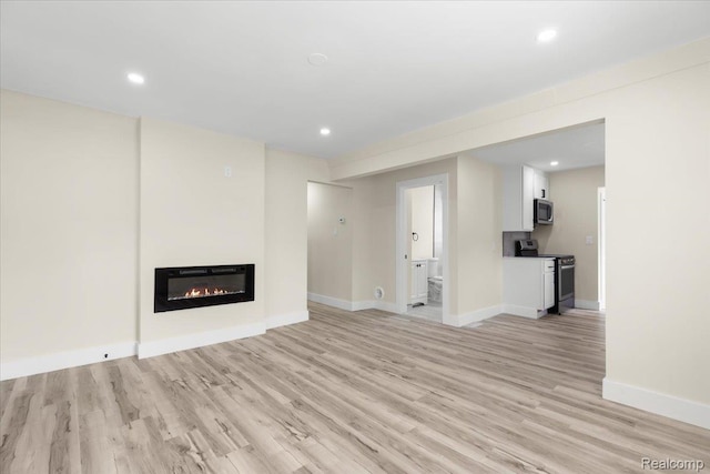 24270 Columbus Ave, Warren, MI 48089 - unfurnished living room featuring light wood-style floors, a glass covered fireplace, and recessed lighting