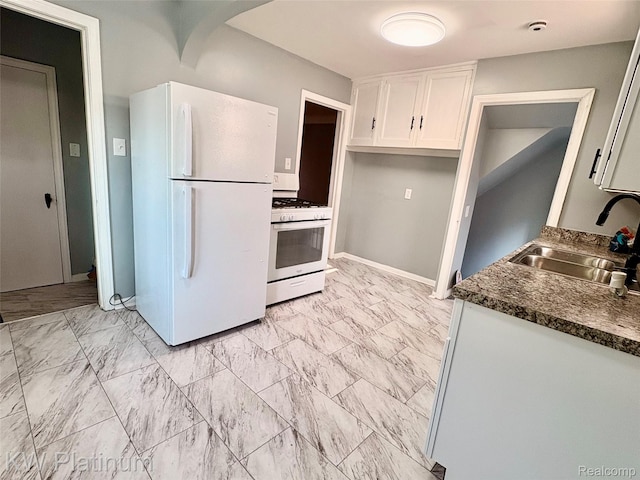 16054 Carlisle St, Detroit, MI 48205 - kitchen with white appliances, dark countertops, light marble finish floors, and white cabinets