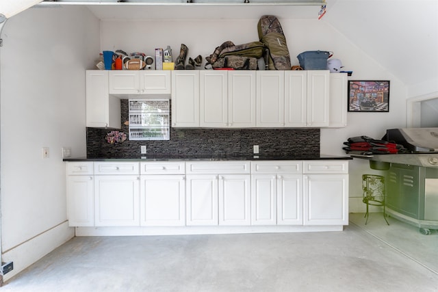 6360 Ray Rd, Swartz Creek, MI 48473 - kitchen with concrete floors, backsplash, dark countertops, white cabinetry, and vaulted ceiling