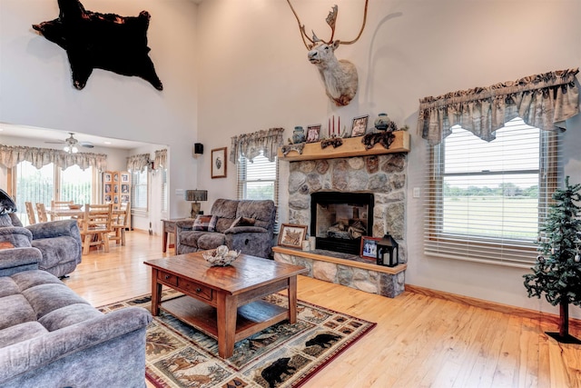 6360 Ray Rd, Swartz Creek, MI 48473 - living area featuring ceiling fan, a fireplace, wood-type flooring, and a towering ceiling