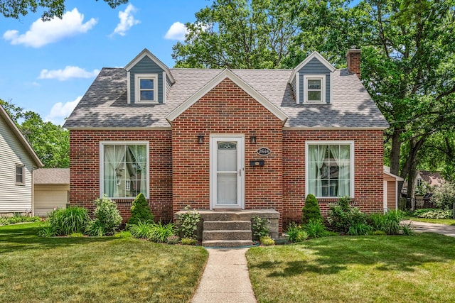 2646 Forest Grove Ave SW, Wyoming, MI 49519 - cape cod-style house featuring a chimney, brick siding, a front lawn, and a shingled roof