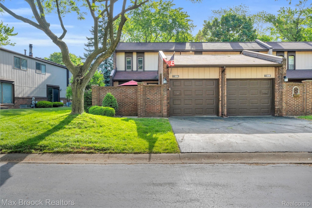 1169 Kirts Blvd Unit 12, Troy, MI 48084 - view of front facade with brick siding, concrete driveway, a garage, and a front yard