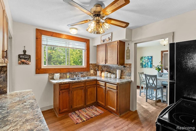 316 N Seymour Rd, Flushing, MI 48433 - kitchen featuring black appliances, light wood finished floors, tasteful backsplash, brown cabinetry, and ceiling fan