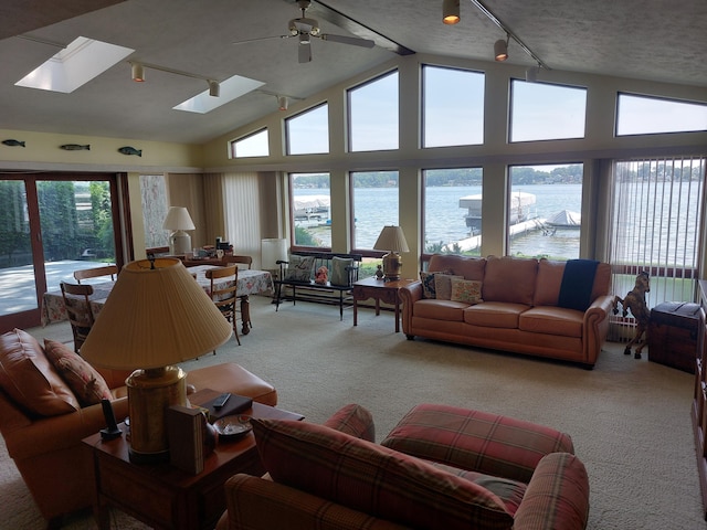 23675 N Shore Dr, Edwardsburg, MI 49112 - living area featuring light colored carpet, a water view, track lighting, vaulted ceiling, and a skylight
