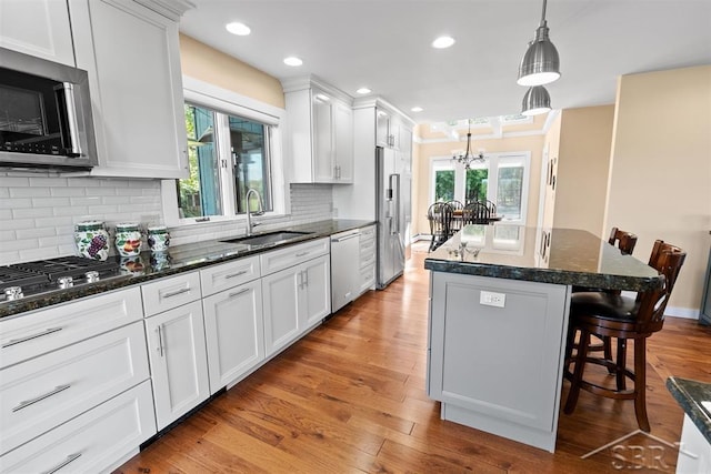 4394 N Francis Shores Ave, Sanford, MI 48657 - kitchen featuring appliances with stainless steel finishes, a breakfast bar, a center island, white cabinetry, and a chandelier