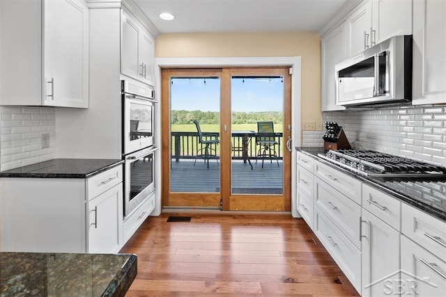 4394 N Francis Shores Ave, Sanford, MI 48657 - kitchen featuring appliances with stainless steel finishes, wood-type flooring, dark stone countertops, white cabinetry, and backsplash