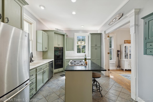 6501 River Rd, Flushing, MI 48433 - kitchen with green cabinetry, appliances with stainless steel finishes, a kitchen bar, decorative backsplash, and crown molding