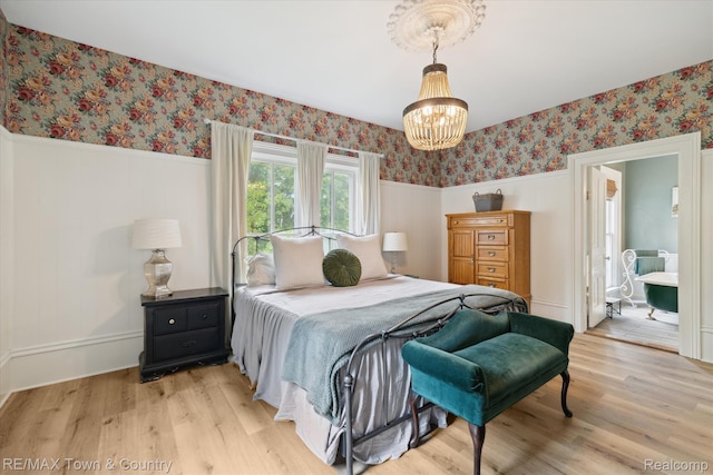 6501 River Rd, Flushing, MI 48433 - bedroom featuring wallpapered walls, a wainscoted wall, light wood-type flooring, a chandelier, and connected bathroom