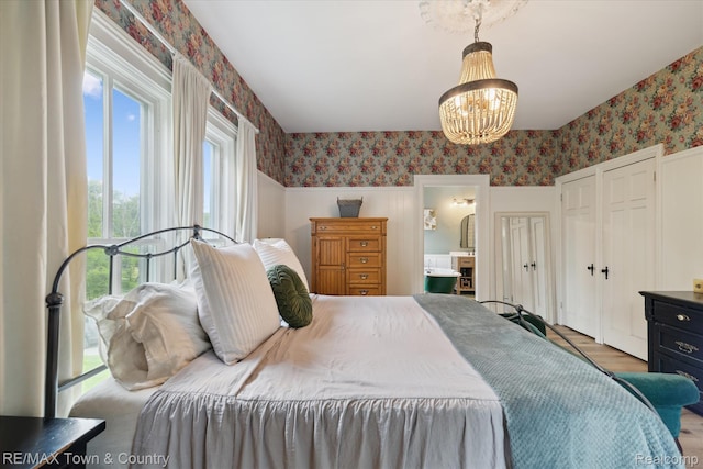 6501 River Rd, Flushing, MI 48433 - bedroom with wallpapered walls, a chandelier, wood finished floors, and ensuite bathroom