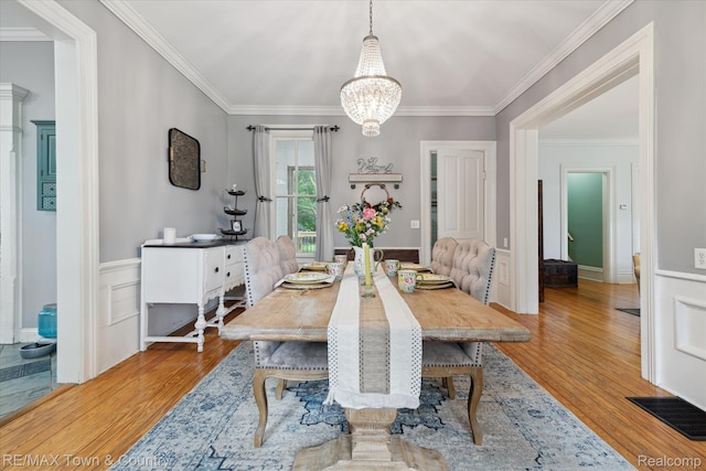 6501 River Rd, Flushing, MI 48433 - dining space featuring a chandelier, crown molding, wood finished floors, and wainscoting