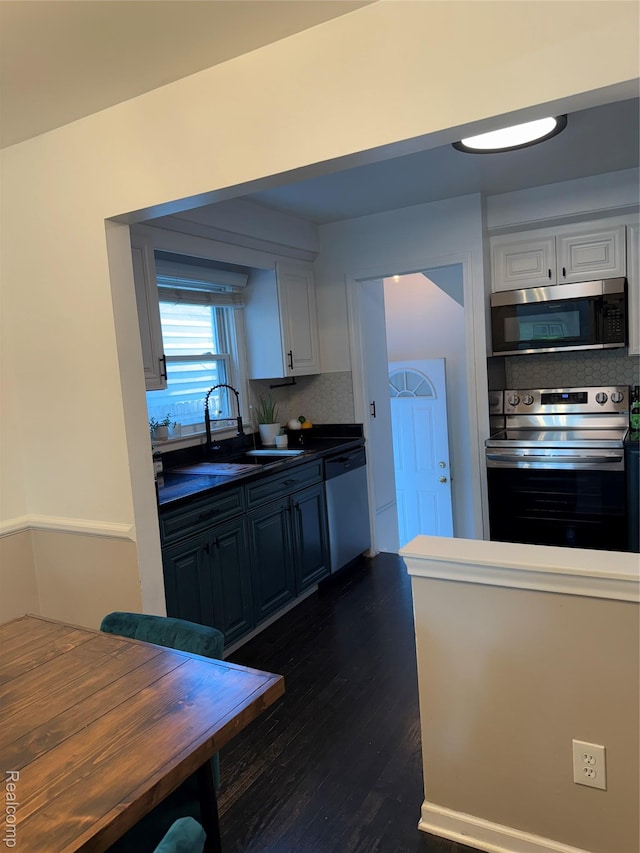 3355 Garden Ave, Royal Oak, MI 48073 - kitchen with stainless steel appliances, white cabinetry, tasteful backsplash, dark wood finished floors, and dark countertops