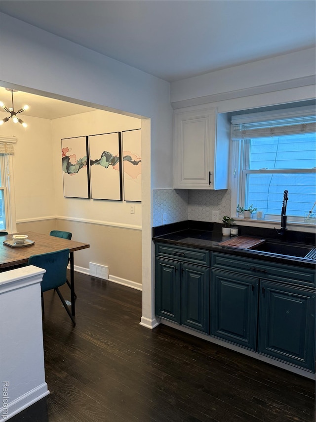 3355 Garden Ave, Royal Oak, MI 48073 - kitchen with dark countertops, dark wood-style floors, white cabinets, a chandelier, and decorative backsplash